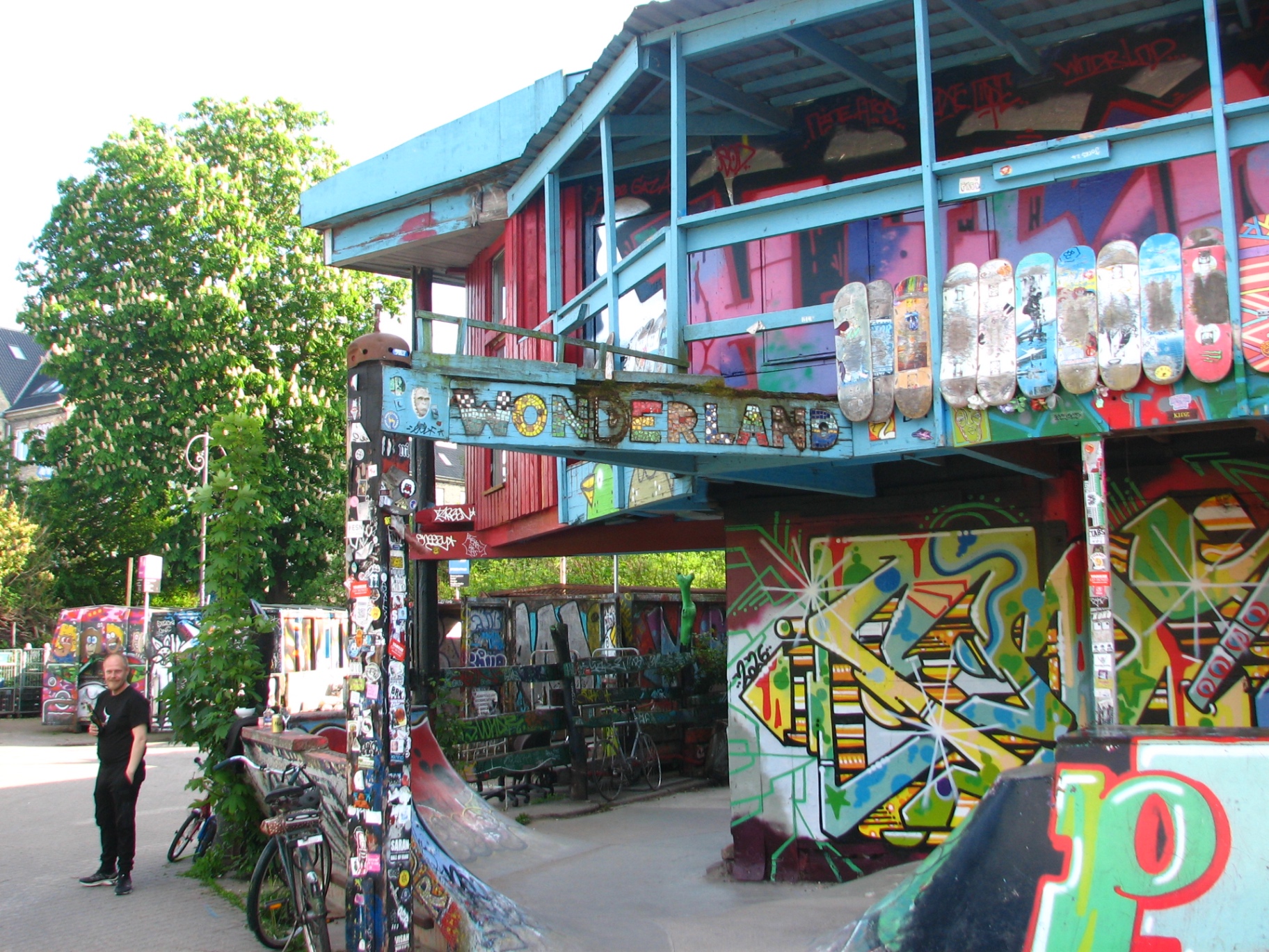 A heavily graffitied wooden pavilion in Christiania with skateboards mounted along its side and a 'Wonderland' sign over the entrance.