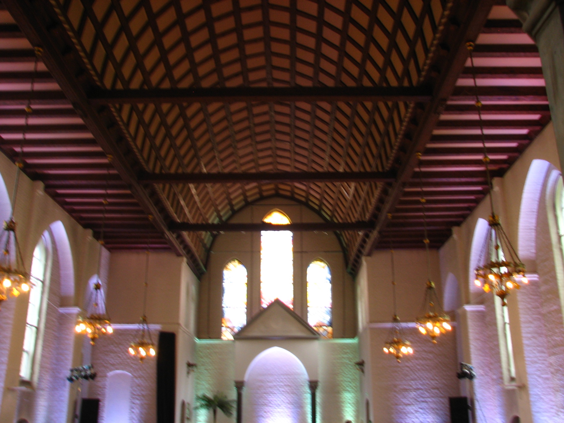 Long view up to the dark wooden coffered ceiling of KoncertKirken, lit warm against the pale brick walls.